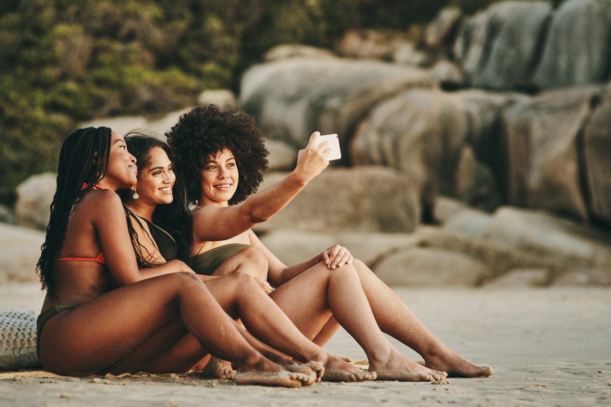 Shot of three friends taking a selfie while spending the day at the beach